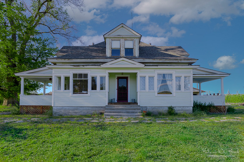 Exterior of a white antique home in Zillah, WA showing blue sky and green yard. Real estate photography service by Kiss of Heaven.
