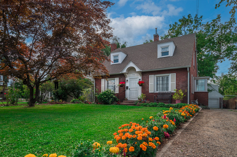 Exterior of a brick home with many flowers and green yard. Real estate photography service by Kiss of Heaven Photography.