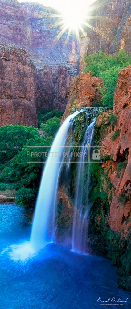 Panoramic fine art photograph of a Grand Canyon waterfall at sunrise, with golden light illuminating the cliffs and cascading water.