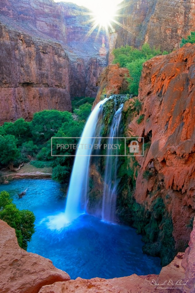 A fine art nature photograph of Sunrise at Havasu Falls in the Grand Canyon, with turquoise waters flowing over travertine rock formations, surrounded by red canyon walls.